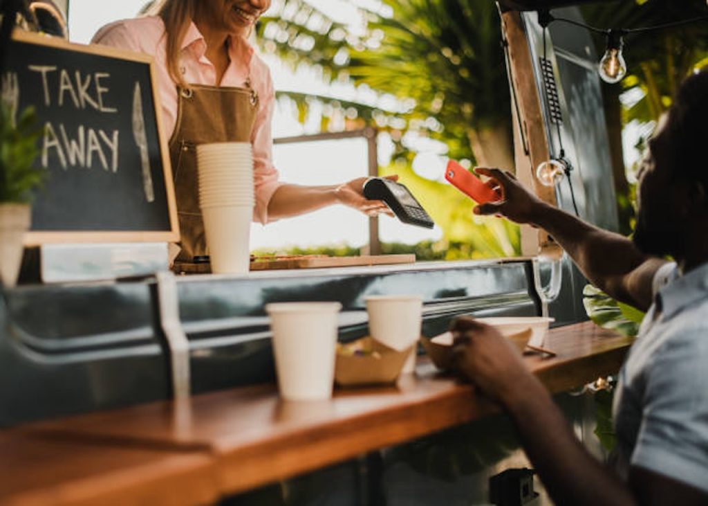 African man making contactless payment at food truck restaurant